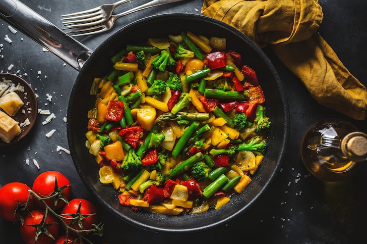 Wok de légumes croquants dans une poêle en fonte : brocolis, haricots verts, asperges, poivrons