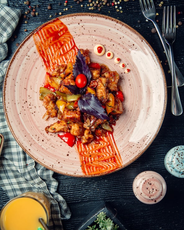 Sauté de poulet caramélisé au basilic pourpre, assiette rose décorée de traits de sauce