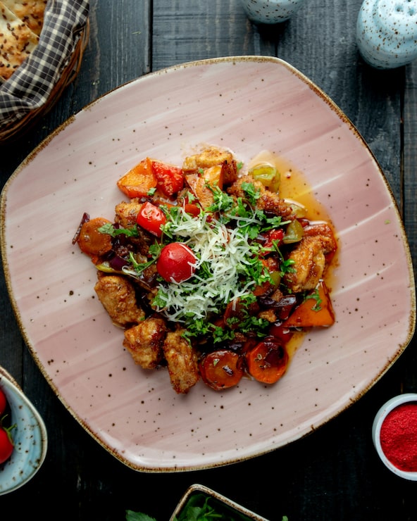 Poulet croustillant aux légumes garni d'herbes fraîches et de parmesan, assiette rose
