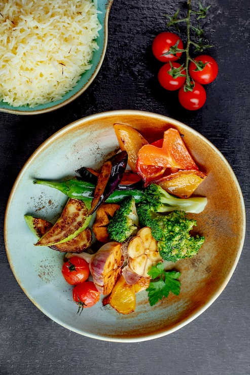 Assiette de brocoli et légumes grillés servie avec un bol de riz safrané