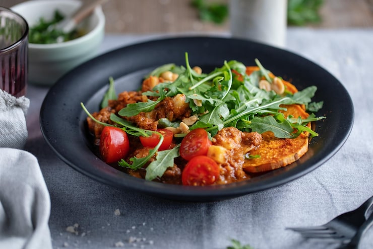 Salade tiède d'automne : patate douce rôtie, sauce épicée, roquette, tomates cerises, cacahuètes