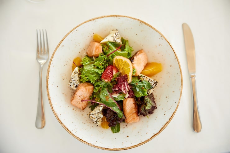 Salade fraîche vue de dessus : dés moelleux, fromage affiné, jeunes pousses, orange et fraise